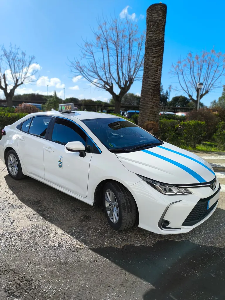 Taxi Toscano, licencia 2 de Huelva: Toyota Corolla blanco con franjas azules y el escudo de la ciudad